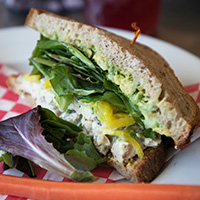 Roasted chicken salad sandwich with avocado, lettuces and pickled onions